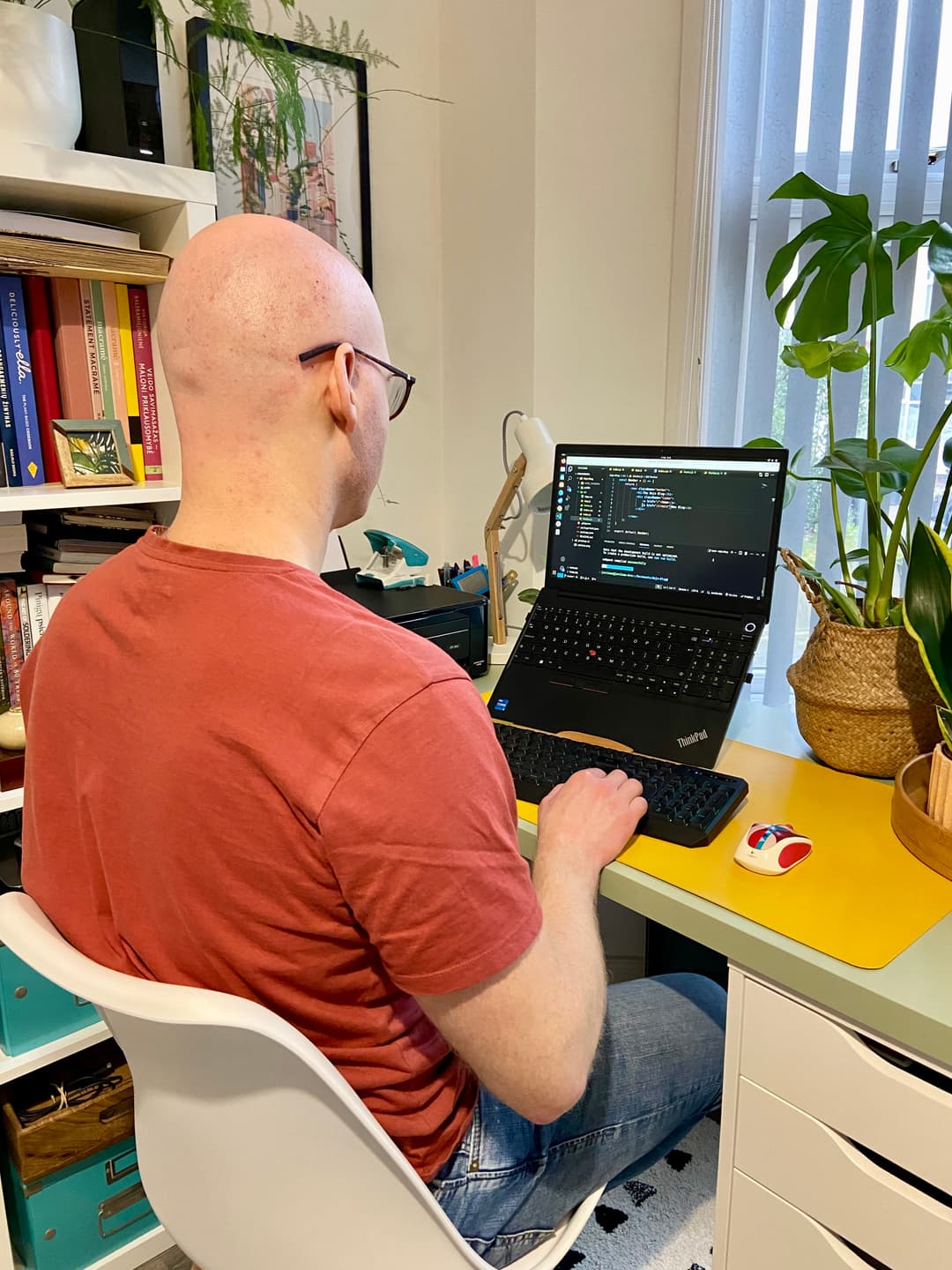 Justinas at his desk, writing code on a ThinkPad laptop